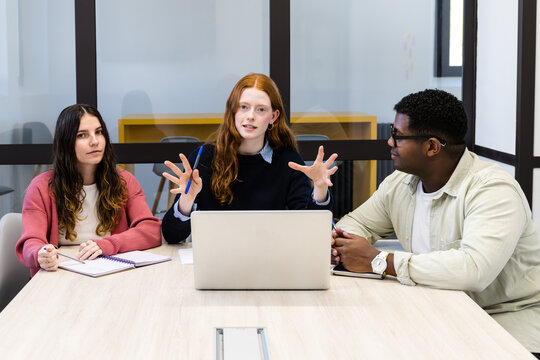 Diverse team meeting around laptop in modern office