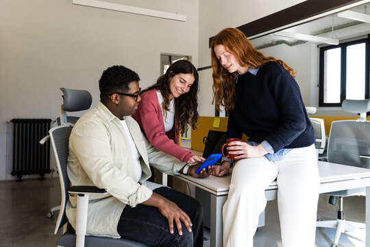 Team reviewing smartphone data together in modern office