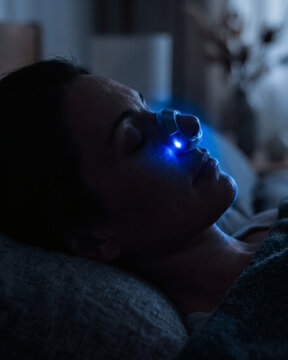 Person sleeping comfortably in profile wearing a modern nasal anti-snoring device.