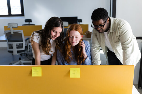 Colleagues collaborating at computer in modern office
