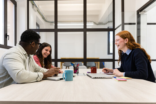 Colleagues laughing during a casual meeting in modern office