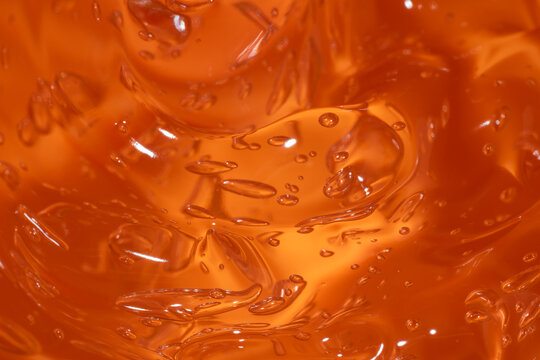 Abstract orange gel texture with glossy smear and bubbles
