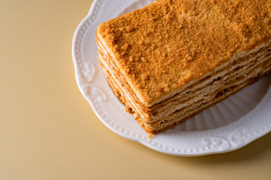 Layered honey cake slice on white plate, bakery dessert