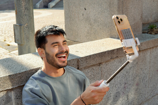 Fashionable urban Hispanic man taking selfie on city street