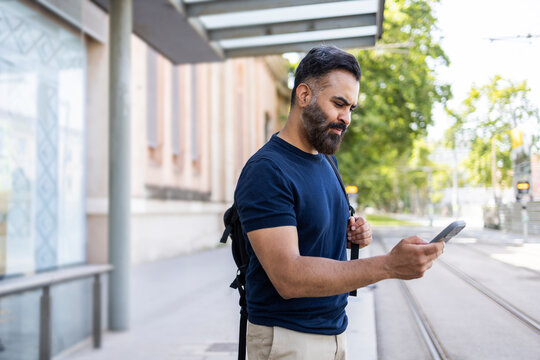 Indian commuter checking phone at outdoor train platform