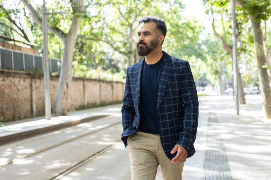Indian man walking by tram tracks on a sunny street