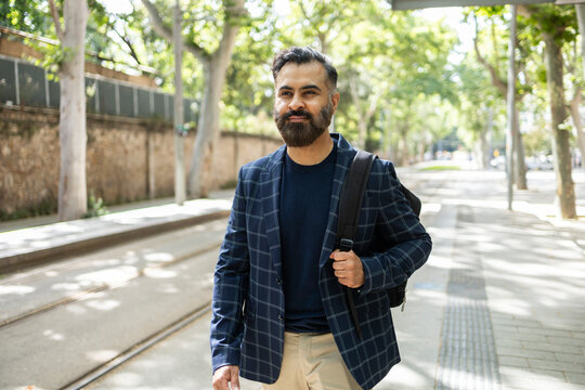 Indian man walking beside tram tracks on sunny street