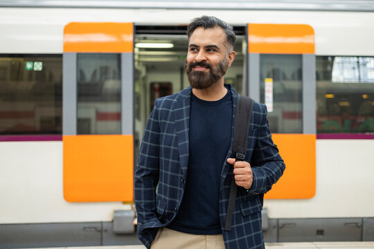 Indian commuter with backpack waiting beside metro train