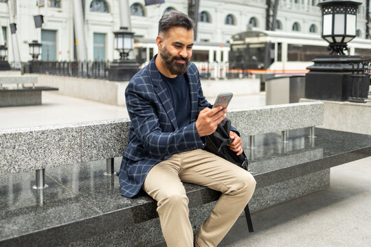 Indian commuter using smartphone while waiting for train