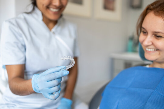 Dentist presenting clear aligner to smiling patient