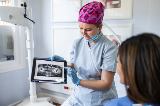 Dentist showing dental X-ray to patient in clinic