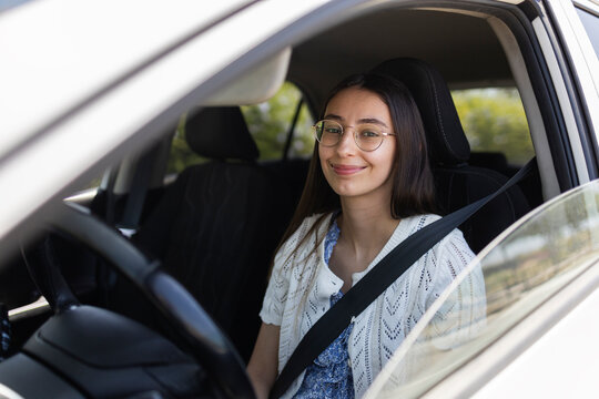 Smiling young woman wearing seatbelt in car driver seat