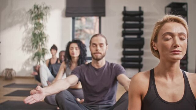 Yogi people sitting in row. Relaxation and practicing meditation. Group of people doing padmasana at yoga studio. People sitting in lotuse pose at yoga class. Coach instructor giving instructions.