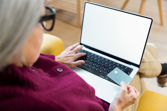 Senior woman using laptop and credit card at home