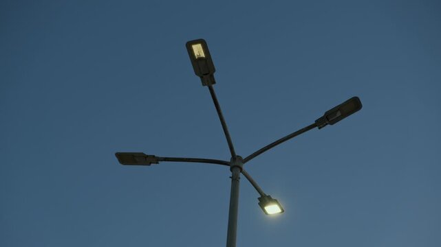 Single blinking street light against deep blue dawn sky creating mysterious liminal atmosphere, minimalist cinematic background with dramatic negative space