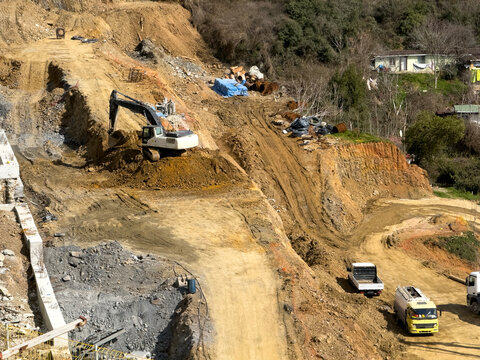 Excavator working on hillside road construction site