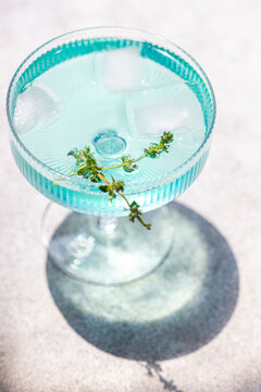 Refreshing blue cocktail with ice and herb garnish