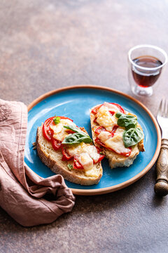 Toast with tomato, basil and parmesano on blue plate
