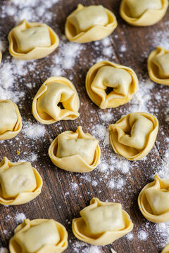 Fresh tortellini on floured wooden board closeup photo
