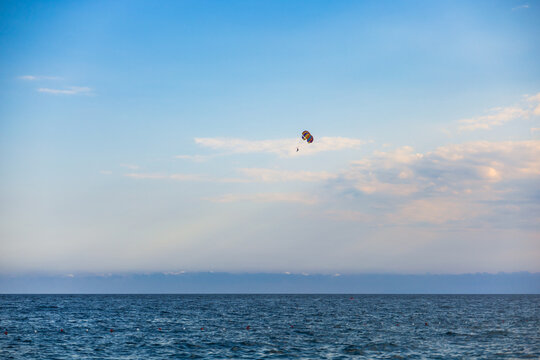 Parasailing above calm sea under blue sky with clouds