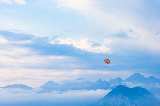Parasailing canopy drifting above misty mountain skyline