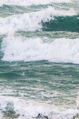 Naklejka premium A breaking ocean wave with white foam rolling over deep blue and turquoise water in soft natural light creating a dynamic and atmospheric coastal scene.