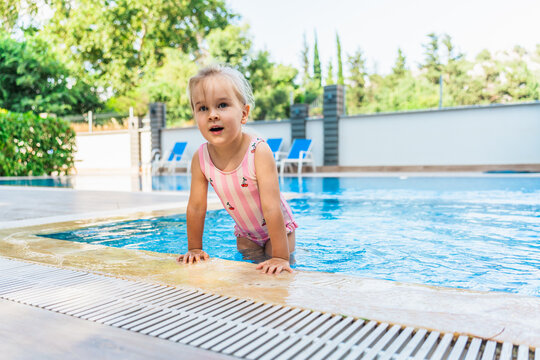 Toddler girl playing at outdoor pool on sunny summer day