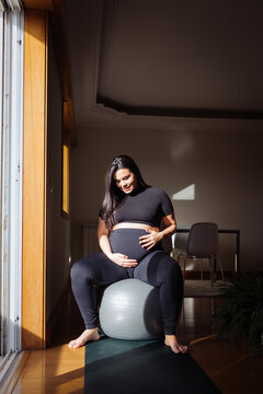 Pregnant woman doing prenatal fitness on exercise ball at home