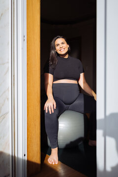 Pregnant woman exercising on stability ball in sunlight