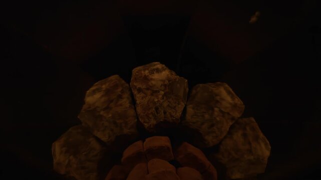 A soft breath of minimalist fire lingers as a glowing cap above a solid granite stone in 1000fps slow motion. Perfect symmetry in wedge mirrors highlights the essence of light. Concept: breath silence