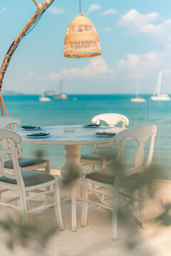 Romantic beach outdoor dining table umbrella parasol ocean view sand shore coast vertical summer scene. Romantic travel vacation holiday couples honeymoon lifestyle getaway background wallpaper design
