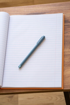 Open blank notebook with pen on wooden desk