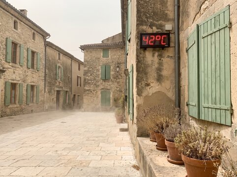 Extreme Heatwave in Europe: Digital Thermometer Showing 42 Degrees Celsius in an Empty Village Street