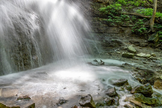 A tranquil view of Sherman Falls' base in Hamilton, Ontario, showcasing cascading water over rocks in a lush forest setting.