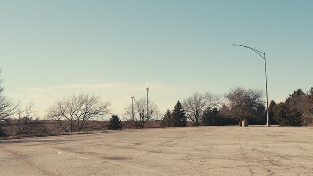 Wind turbines spinning behind an empty parking lot