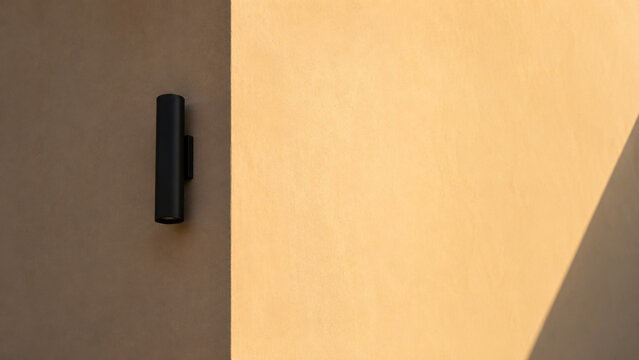 Black Wall Sconce Casting Warm Light on Beige Wall