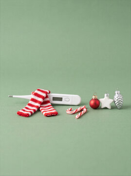 Digital thermometer with knitted scarf and Christmas candy canes for winter fever concept
