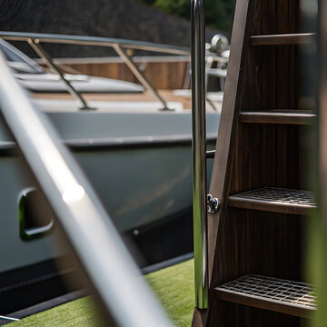 Yacht stairway with polished metal handrail and wooden steps detailed photo with blurred background boat