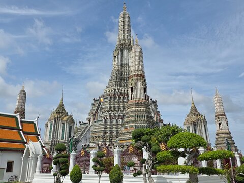 BANGKOK, THAILAND - June 26, 2026: The majestic central prang of Wat Arun temple decorated with colorful porcelain by the Chao Phraya River.