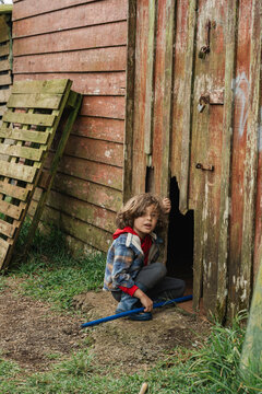 Curious child exploring old wooden shed outdoors