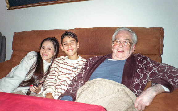 Senior man with grandchildren sitting on a sofa at home