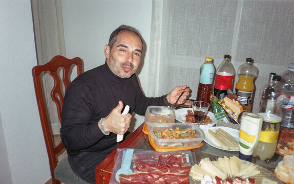 Smiling man gesturing thumbs up during a meal at home