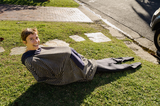 UGC Woman putting on wetsuit on grass before surfing in a funny way