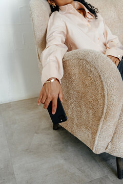 Businesswoman Relaxing in Armchair While Holding Smartphone