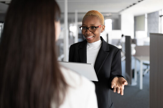 Optimistic black female manager discussing project with colleague