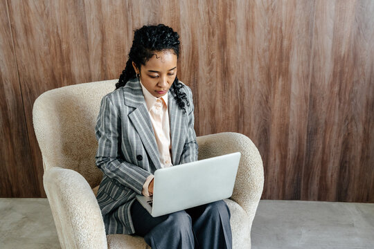 Focused Businesswoman Working on Laptop in Modern Office Lounge