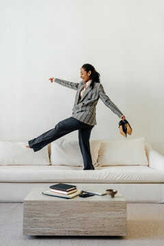 Joyful Businesswoman Balancing Barefoot on Sofa After Work 
