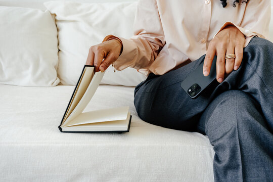 Professional Woman Reviewing Notes While Holding Smartphone on Sofa
