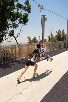 Girl Pushing Boy On Zip Line In A Sunny Outdoor Playground