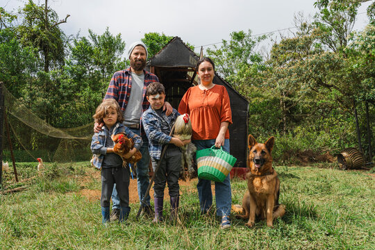 Family of four farming with chickens and a dog
